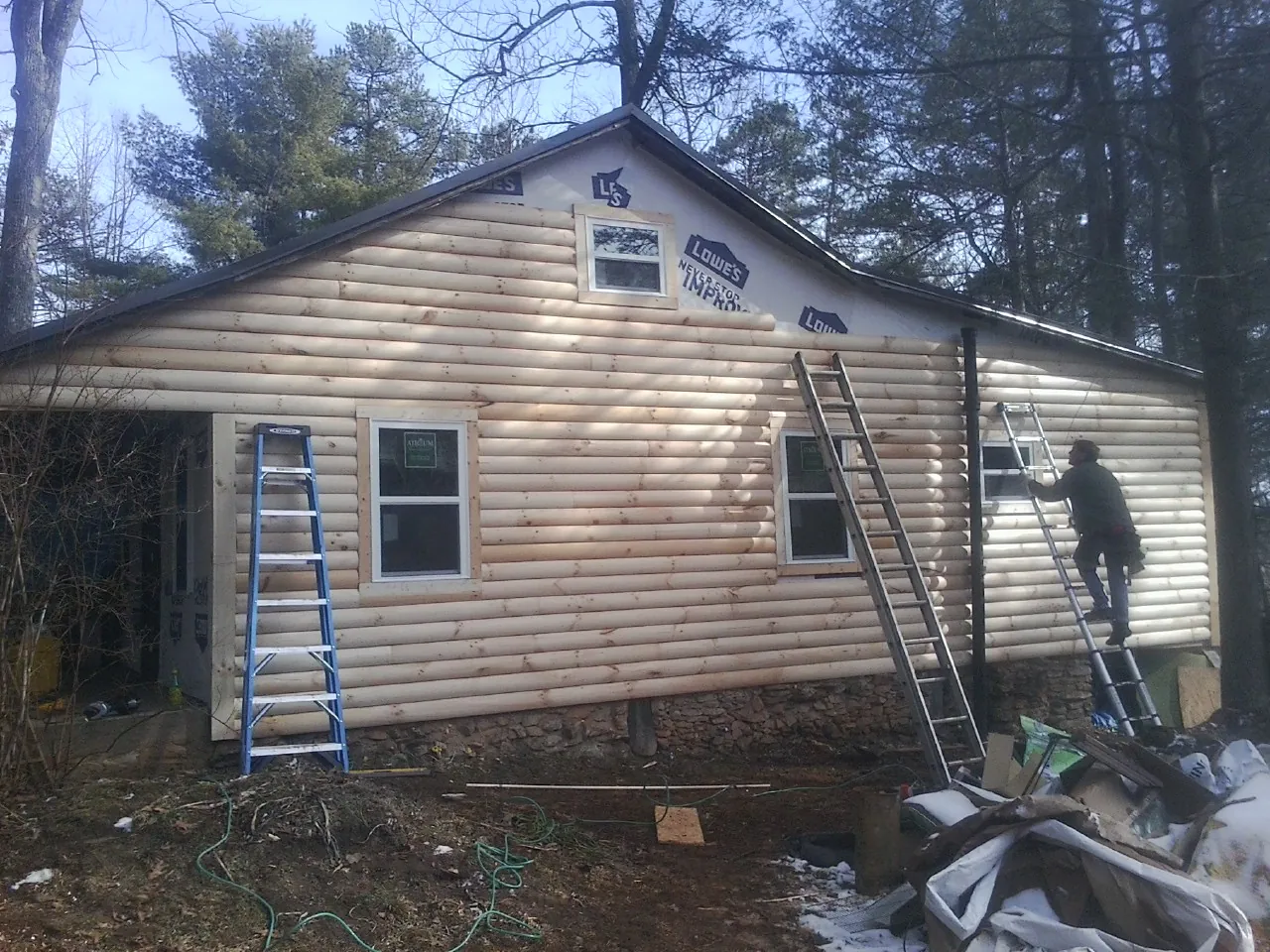 Ladders set against fresh log siding during an exterior remodel in Spanish Fort