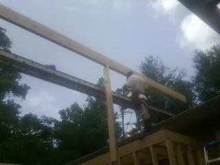 Carpenter setting a ridge beam over a new addition frame — Ice Dam Removal by Roofing Brothers in Spanish Fort
