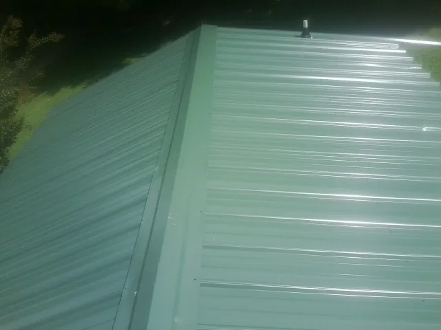New green metal panels meeting at the ridge of a roof — Flat Roof Repair work by our crew in Spanish Fort