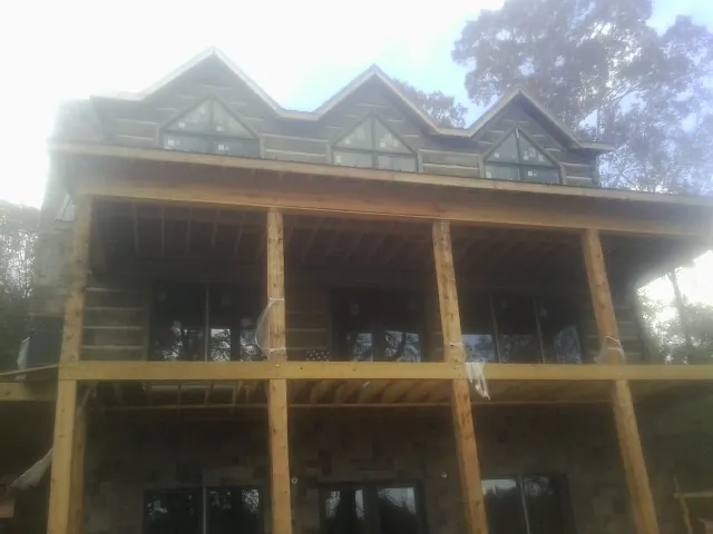 Dormers and porch framing on a large log home under construction — Roof Coating work by our crew in Spanish Fort