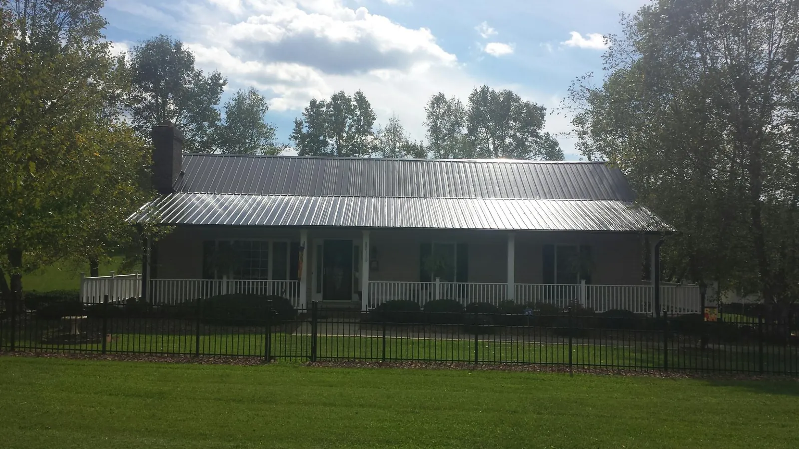 Gray metal roof on a brick ranch with a full width front porch — Gutter Guard Installation work by our crew in Spanish Fort