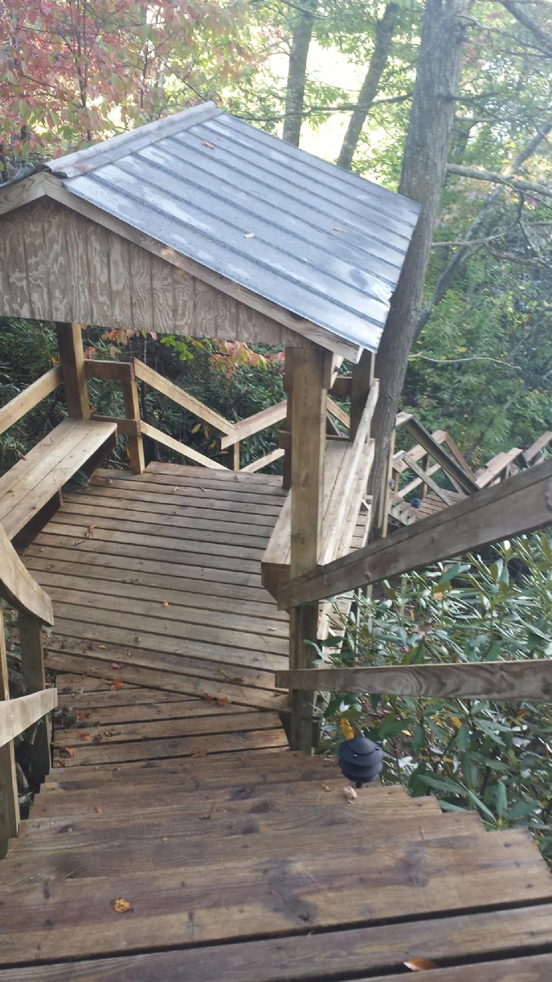 Metal roofed shelter over wooden steps on a wooded walkway — Skylight Repair & Installation work by our crew in Spanish Fort
