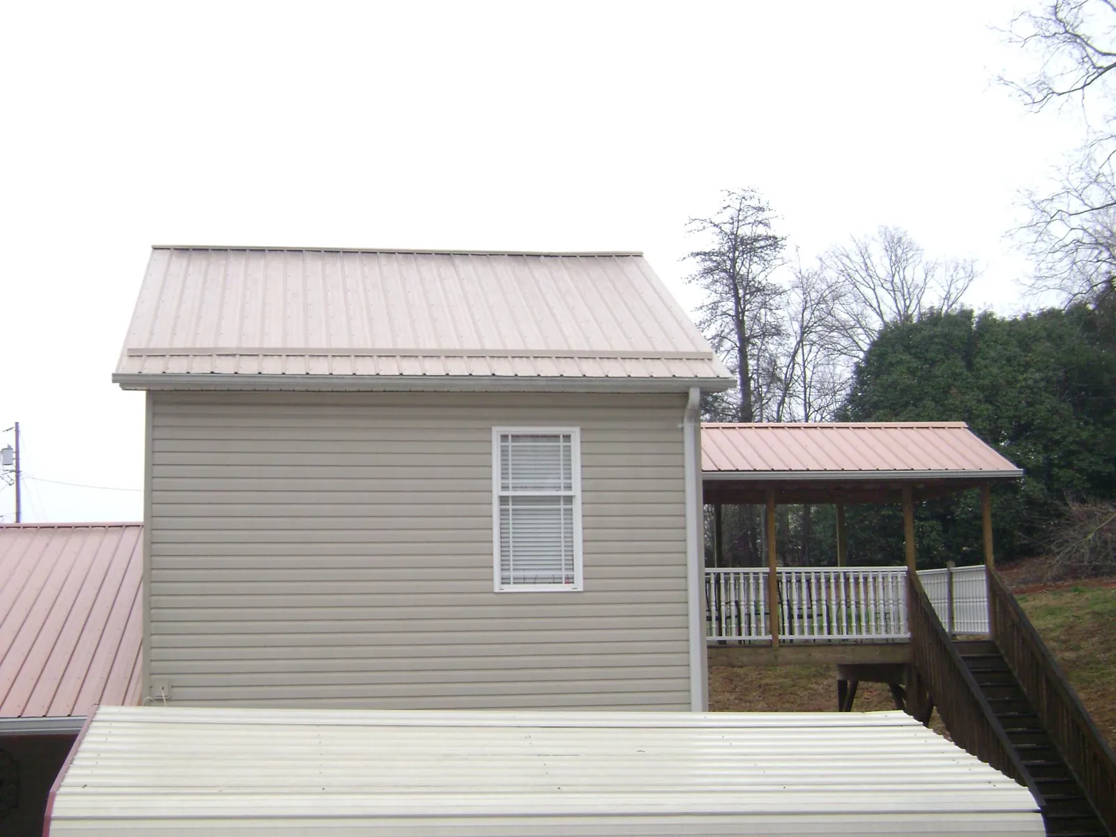 Tan metal roofs on a two story addition and attached porch, from a Roof Replacement job in Spanish Fort