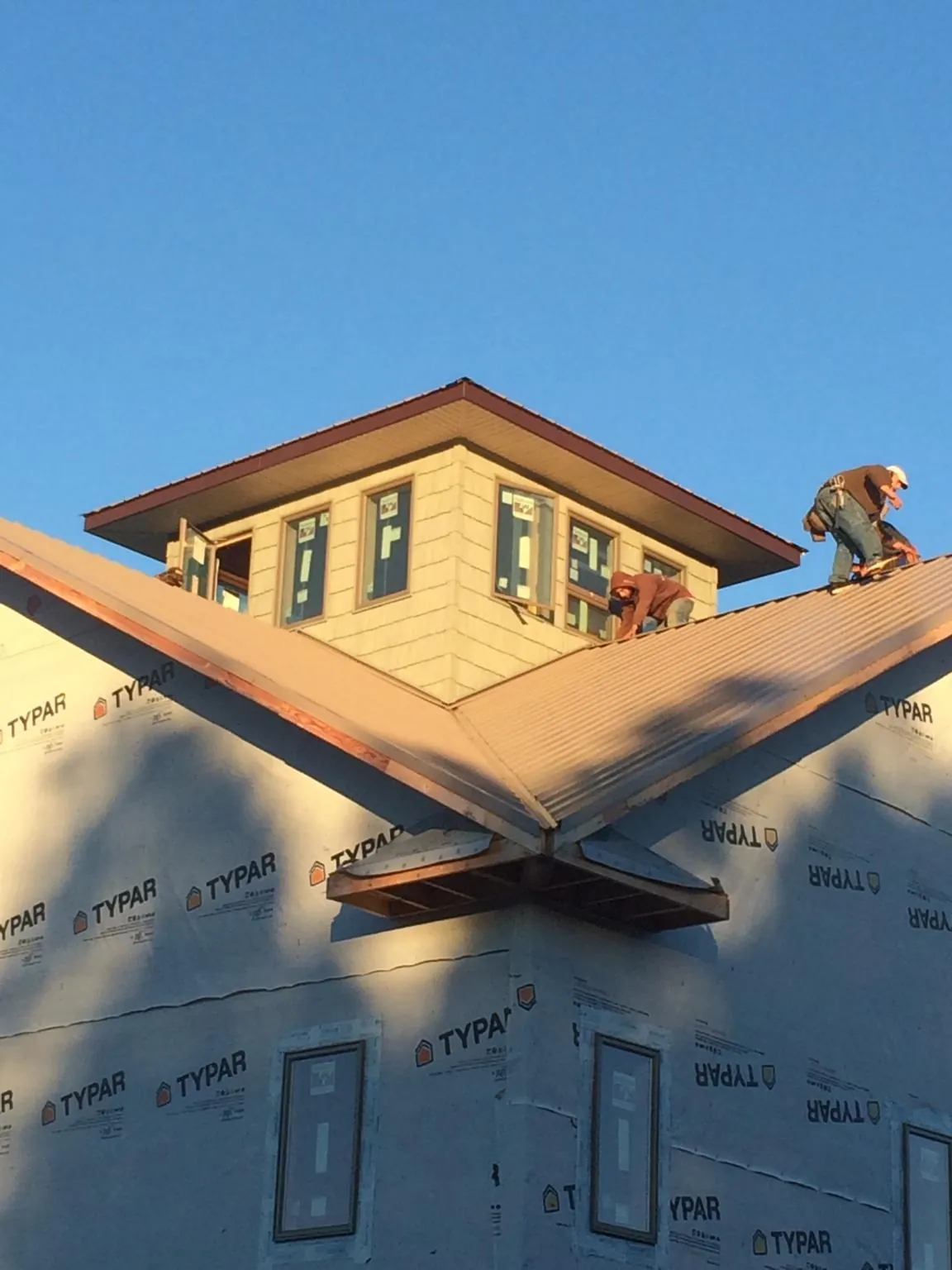 Roofers working around a rooftop cupola on a new metal roof at sunset — Roof Waterproofing in Spanish Fort by Roofing Brothers